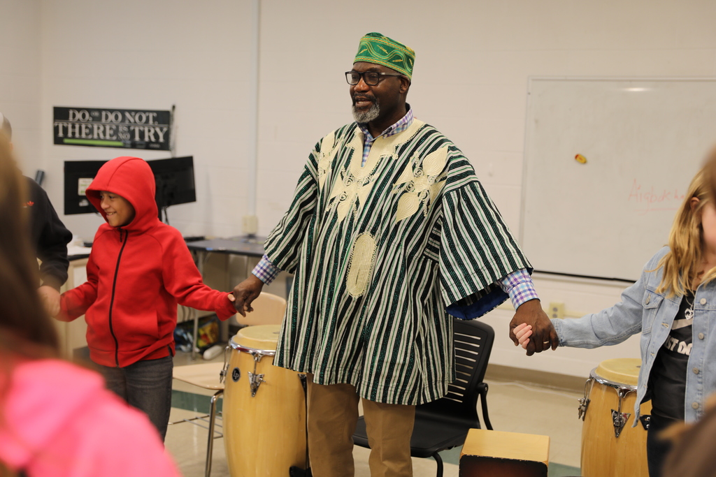 Aloja holding hands with students 