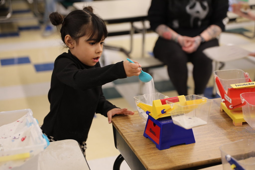a student dumping sand into a toy scale