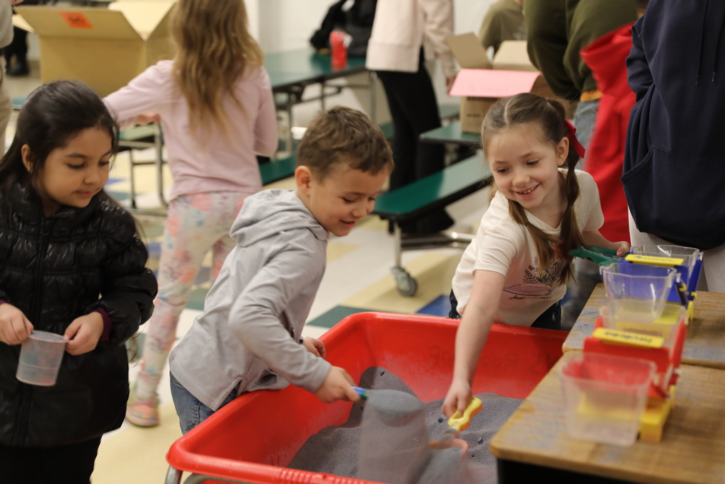 three students playing with the sifting sands in a tub