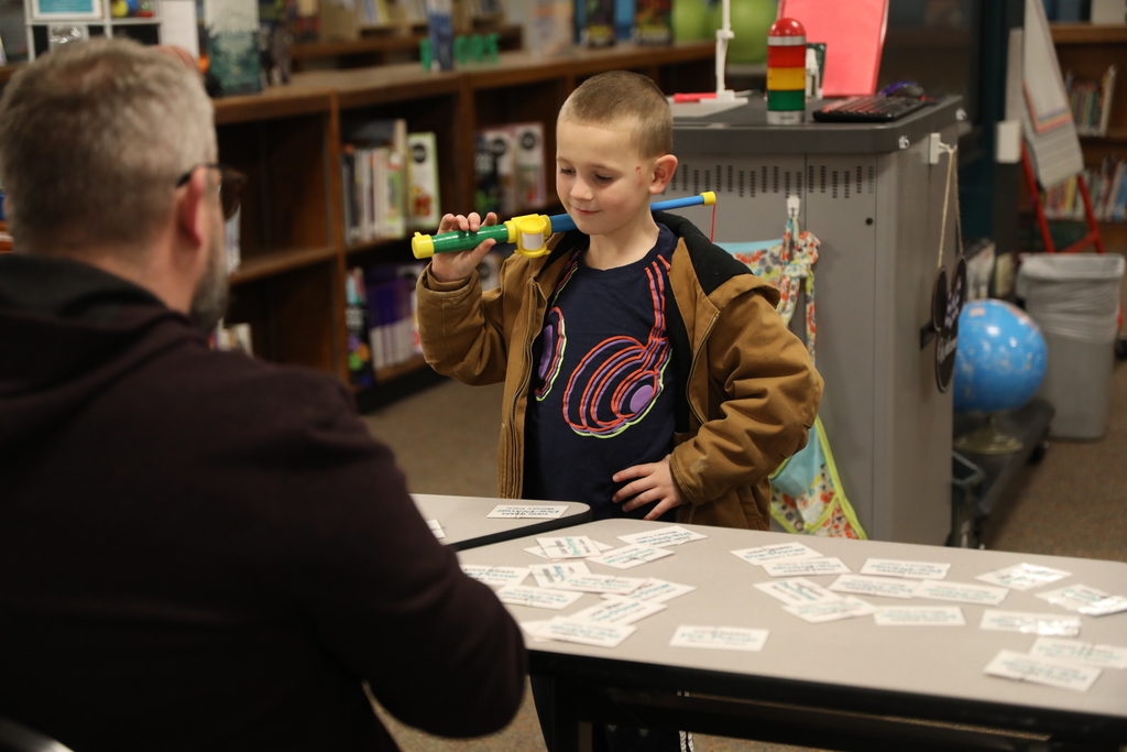 a student holding a toy fishing pole over his shoulder