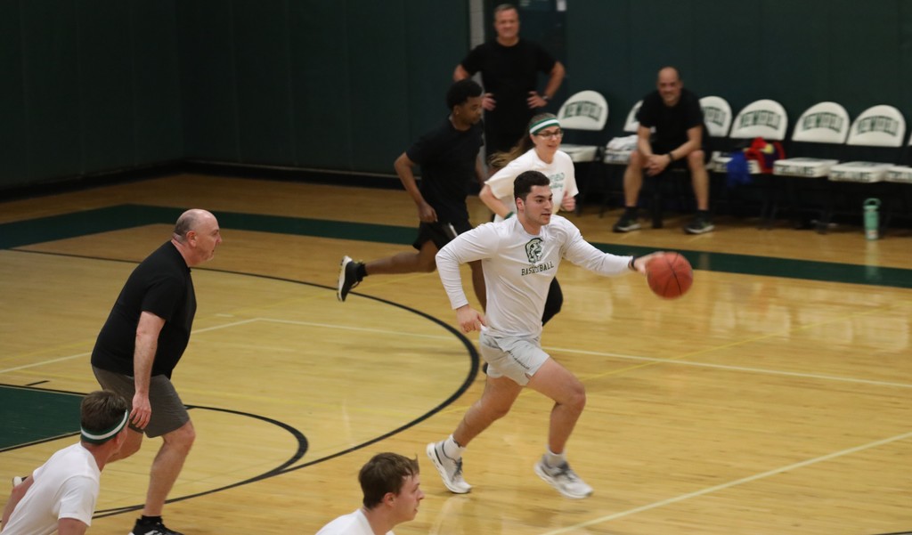 a staff member running down the court with the ball as others chase