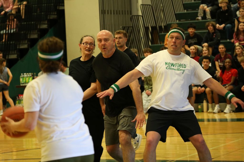 several staff members playing basketball, one is blocking another