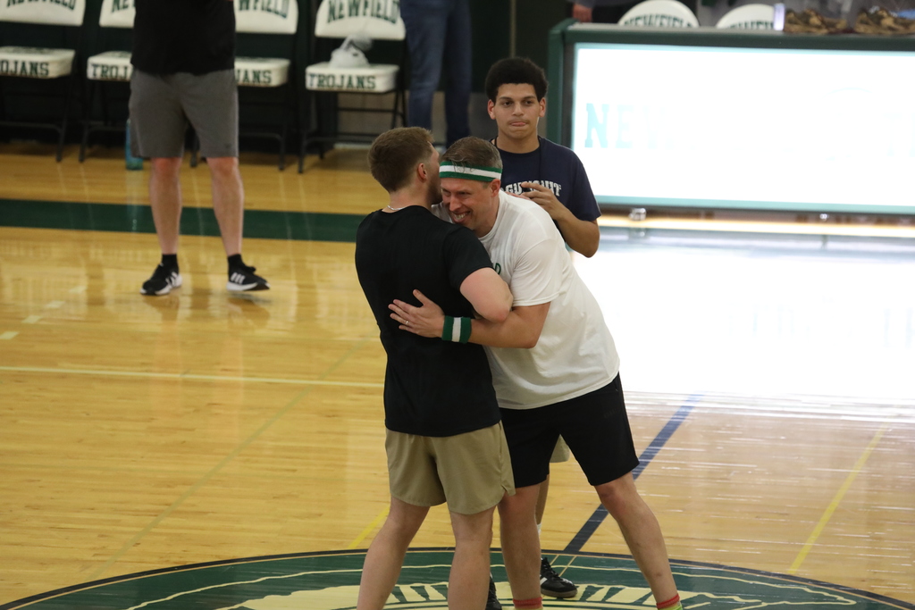 Two staff shaking hands and hugging before the game starts