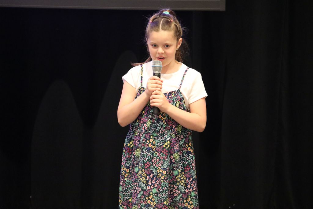 A student reading her poem on stage