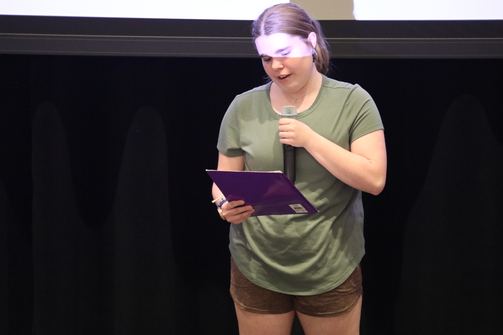 A student reading her poem on stage