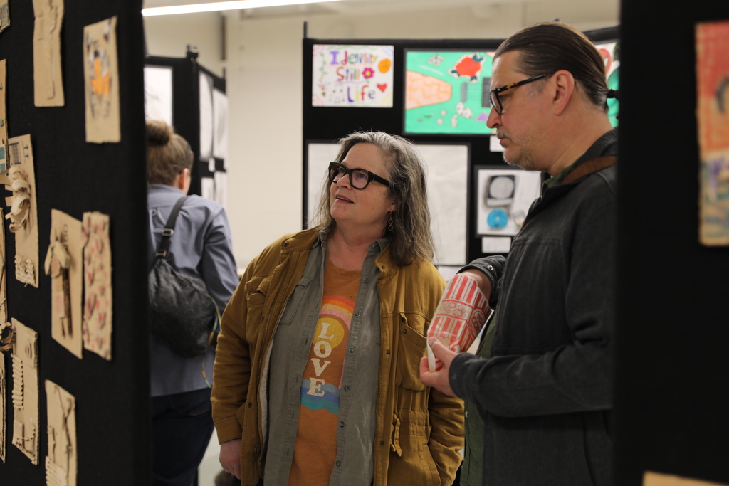 two parents looking at the student art