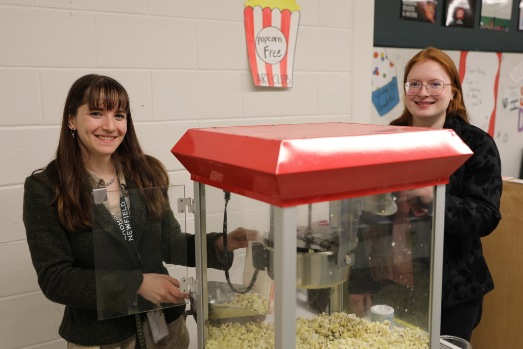two staff members smiling for camera at the popcorn machine