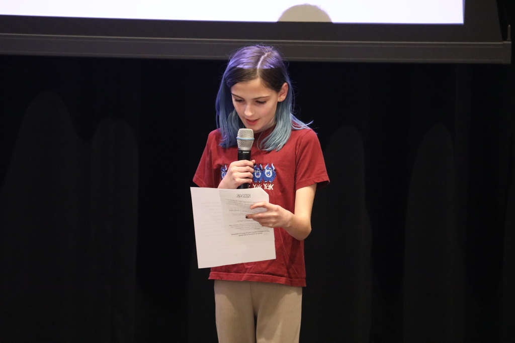 A student reading their poem on stage