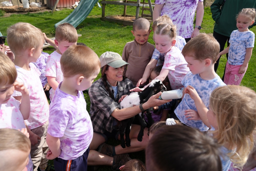 Pre-K students gathered around while bottle-feeding a baby goat during their visit to Daisy Hollow Farm.