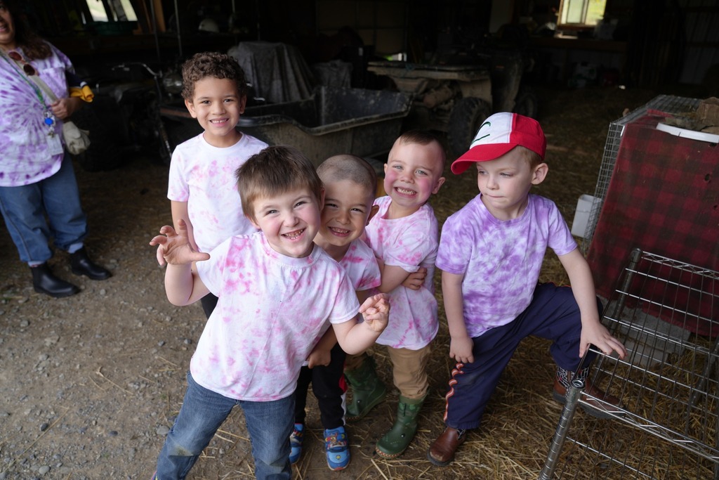 Group of smiling Pre-K students posing together inside a barn during their visit to Daisy Hollow Farm.