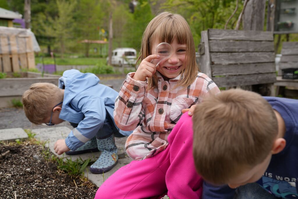 a student looking at camera through a magnifying glass