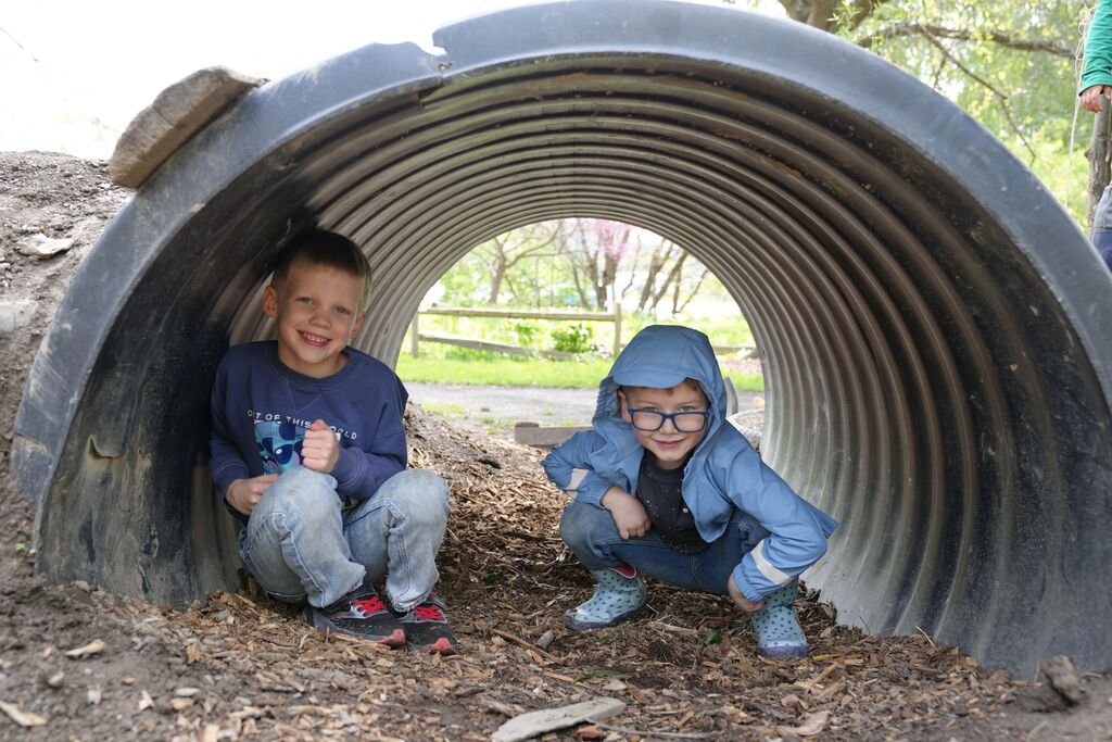 two students posing for the camera under a tunnel pipe
