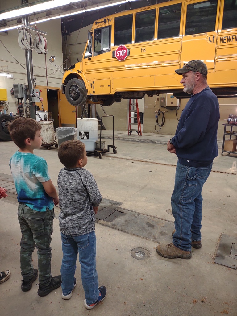 Students talkin to a transportation staff member while looking at a bus