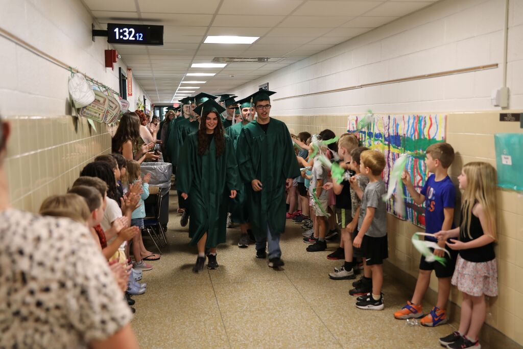 seniors walked down a hall as everyone cheers them on