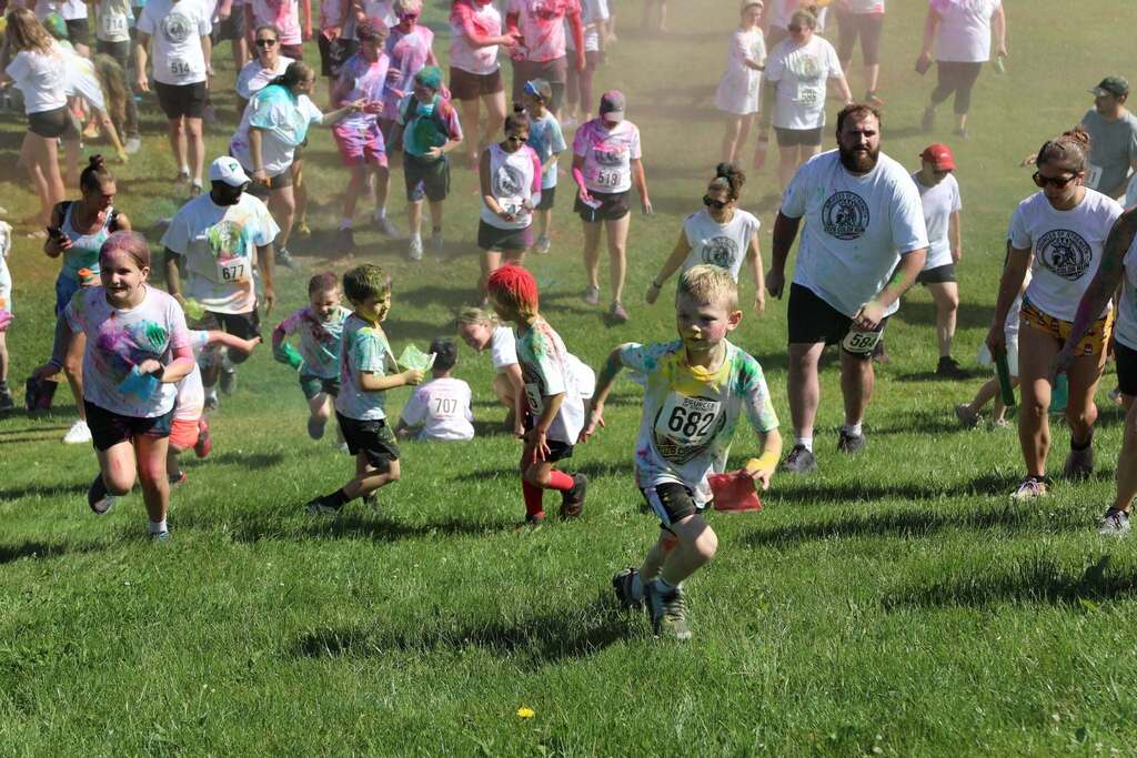 a large group of people running back up the hill after getting color thrown everywhere