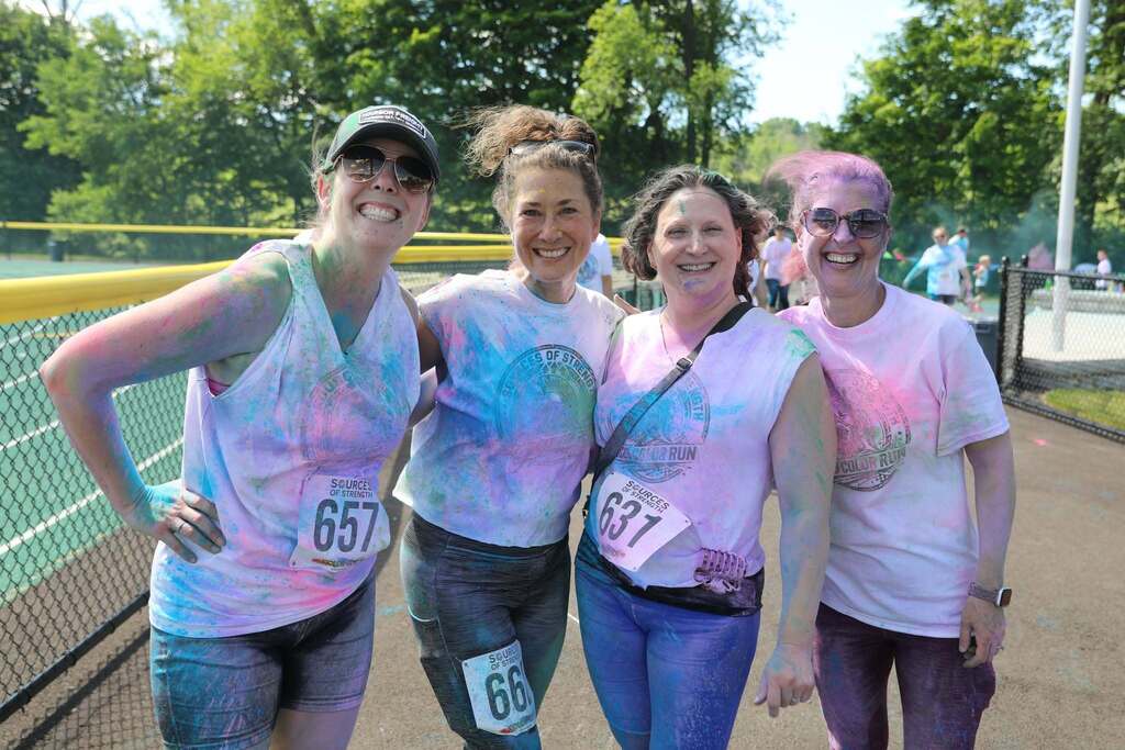 a group of parents posing for the camera after the color run