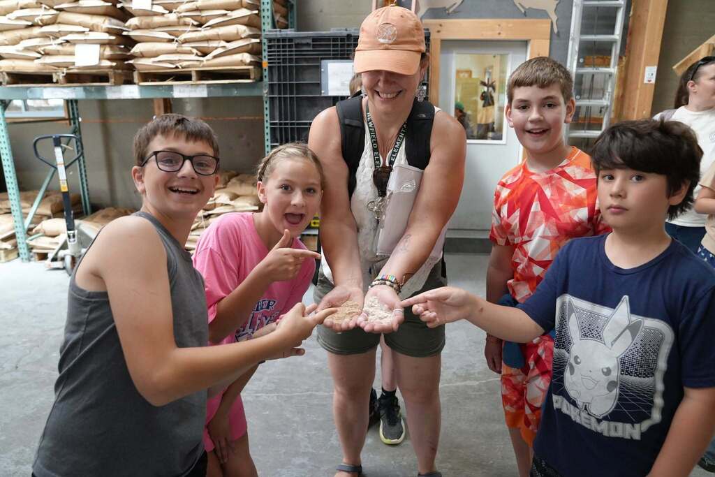Students and an educator compare wheat kernels and flour during a hands-on lesson about how grain is transformed into food products.
