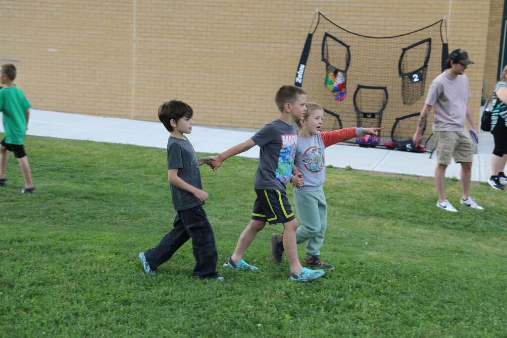 three students holding hands while walking around