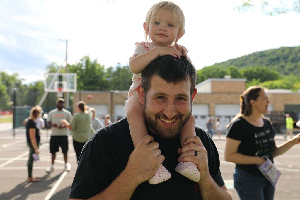 a parent holding a young child on his shoulder