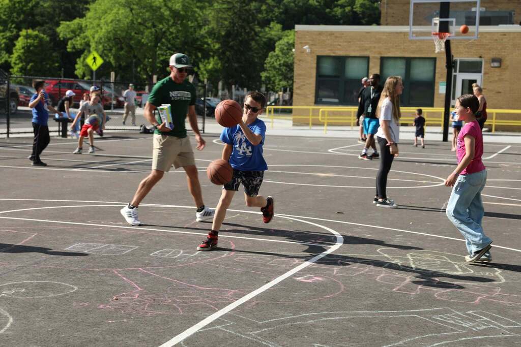 a student playing basketball with two basketballs
