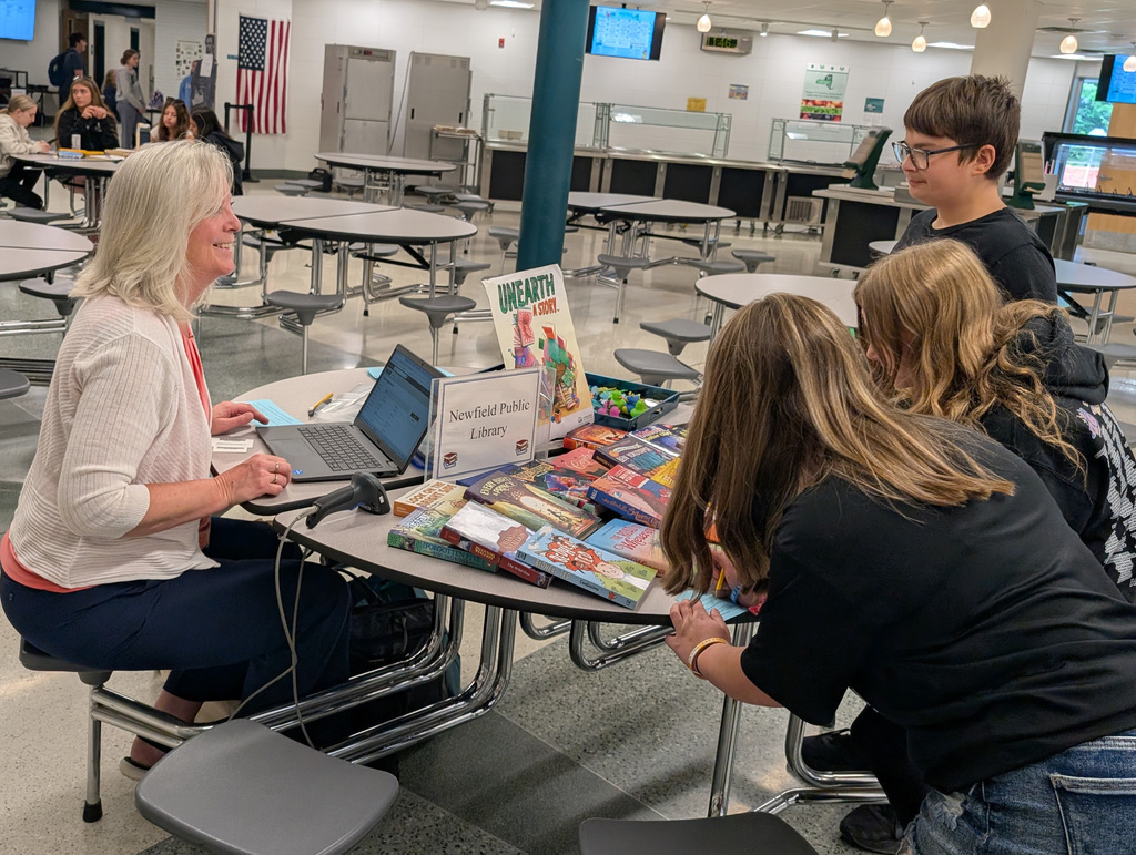 some students and an adult at a table looking at books