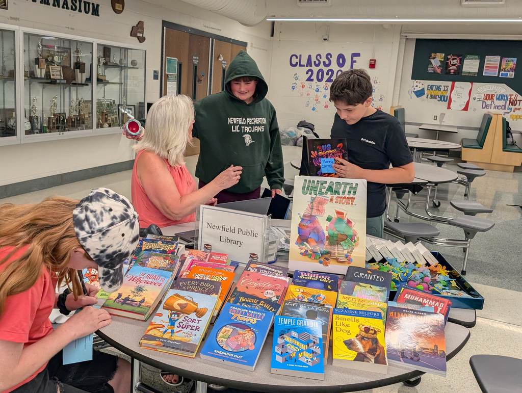 some students and an adult at a table looking at books