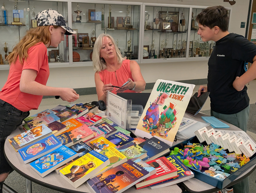some students and an adult at a table looking at books
