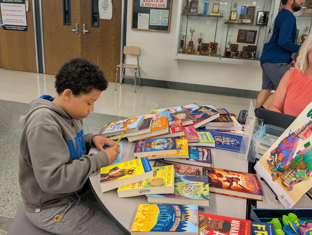 a student writing something at a table full of books