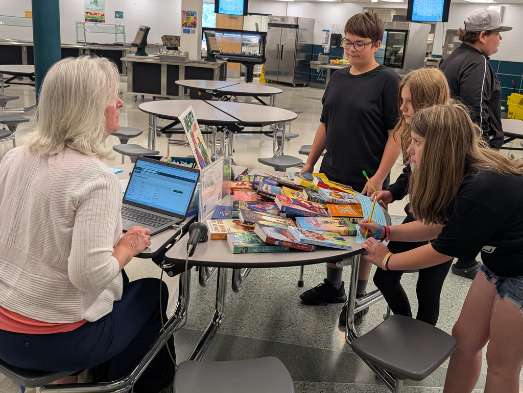 some students and an adult at a table looking at books