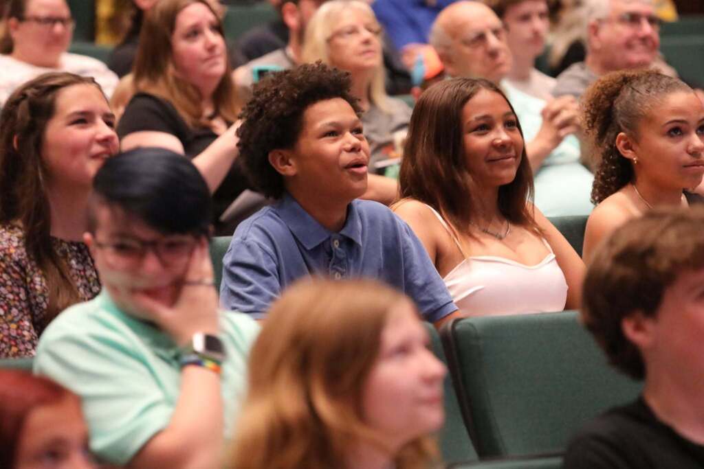 a pic of students in the crowd looking on at the stage