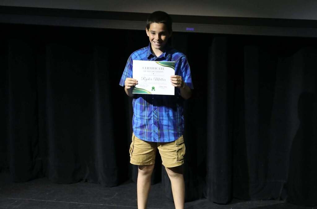 A student on stage holding up a certificate 