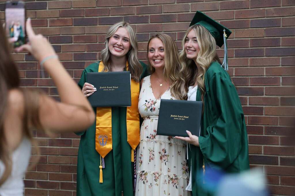 a teacher posing with two graduates