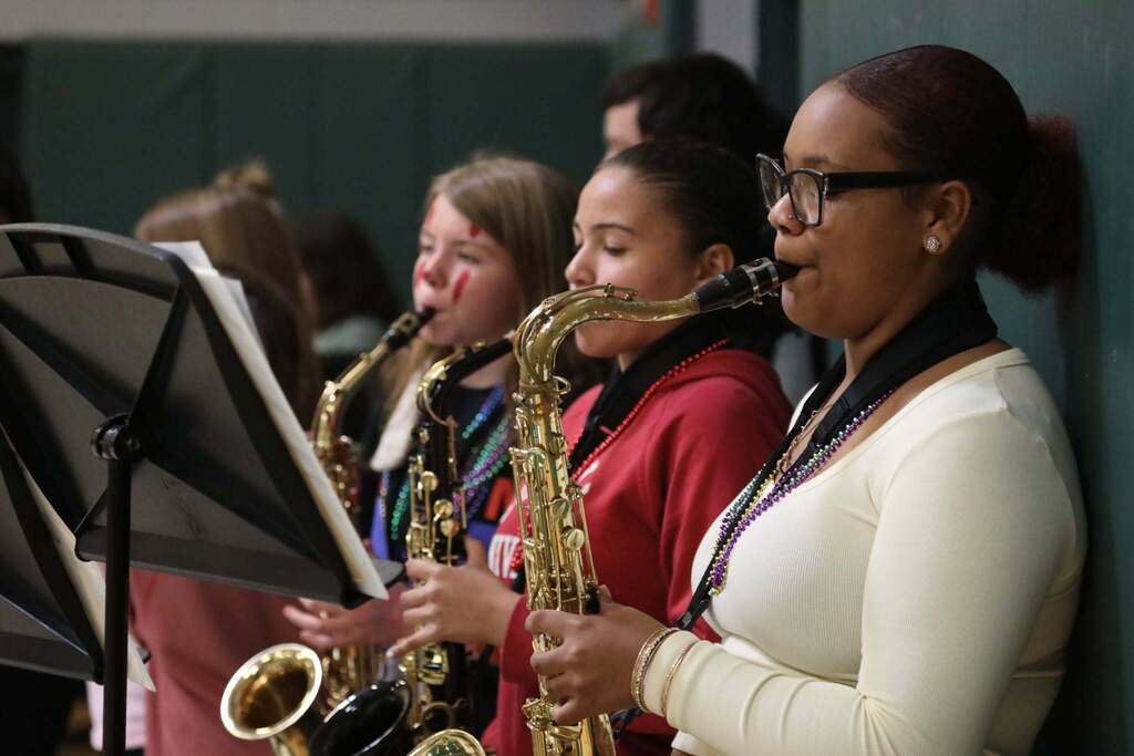 three students playing horns in the band