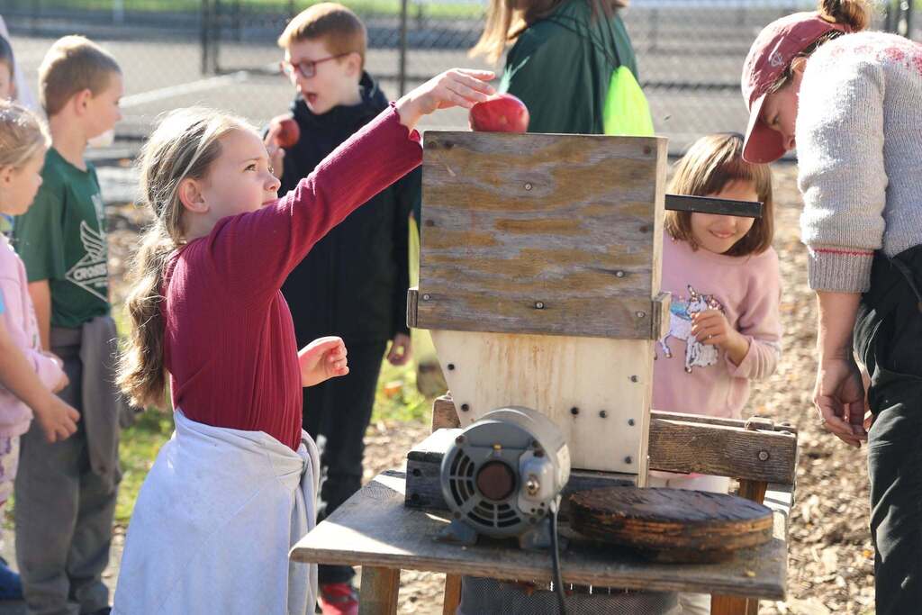 a student putting an apple into the apple press