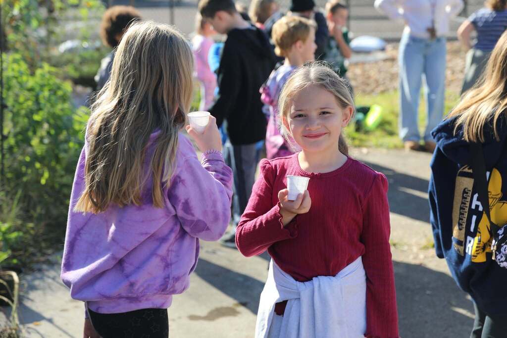 a student holding up her cup of cider
