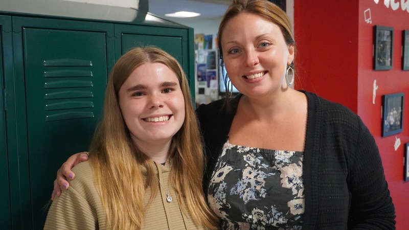 Student smiling with teacher Liz Kozlowski outside of her classroom