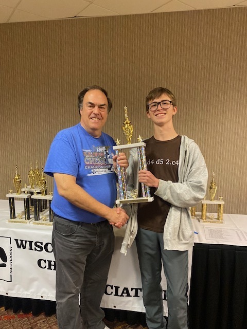 a picture of a man congratulating a boy for winning a trophy