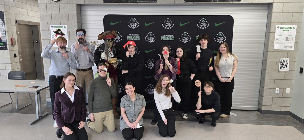 A group of people dressed in costumes pose for a photo in a room with a black backdrop.
