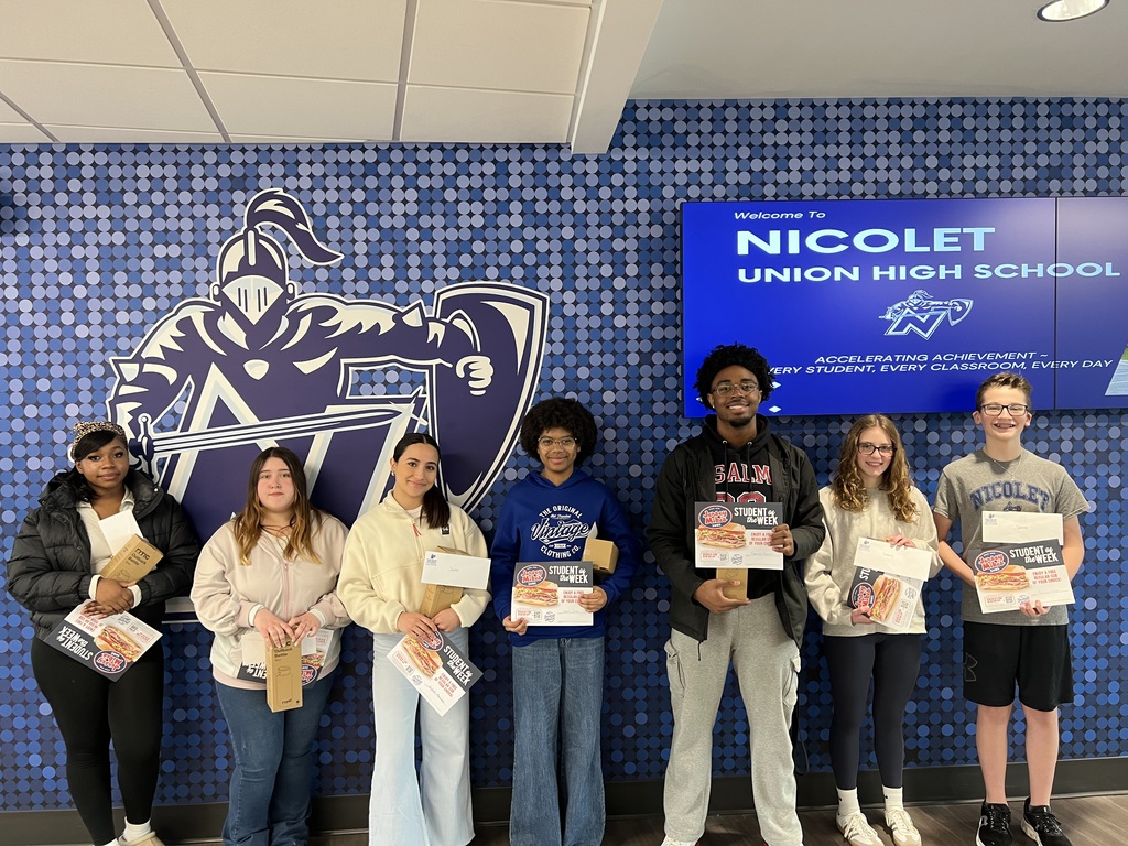 Students stand in front of a wall featuring a school logo, with a sign reading "Nicolet Union High School". They hold certificates.
