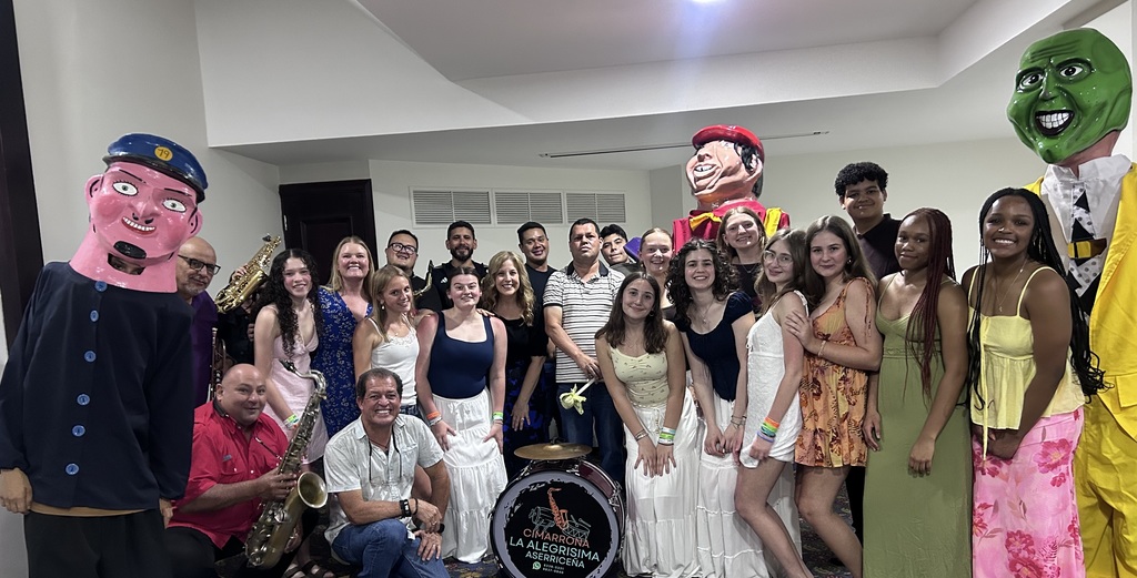 Group of people in a room wearing costumes and holding instruments, posing for a photo.