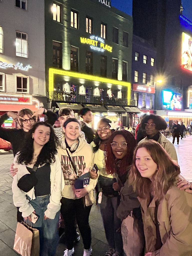 A group of people standing on a city street, smiling and posing for a photo.