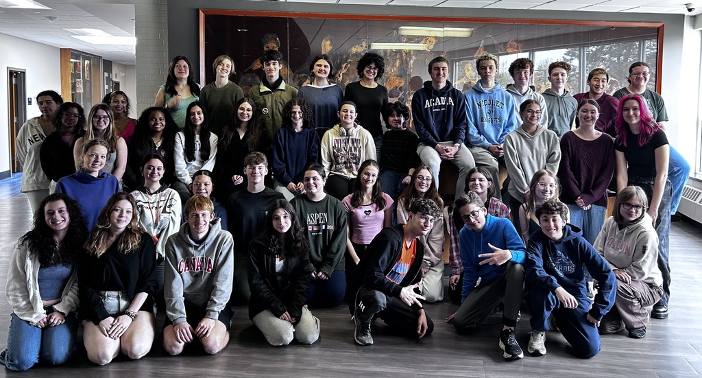 A group of young people, some standing, some sitting, posing for a photograph in a room.