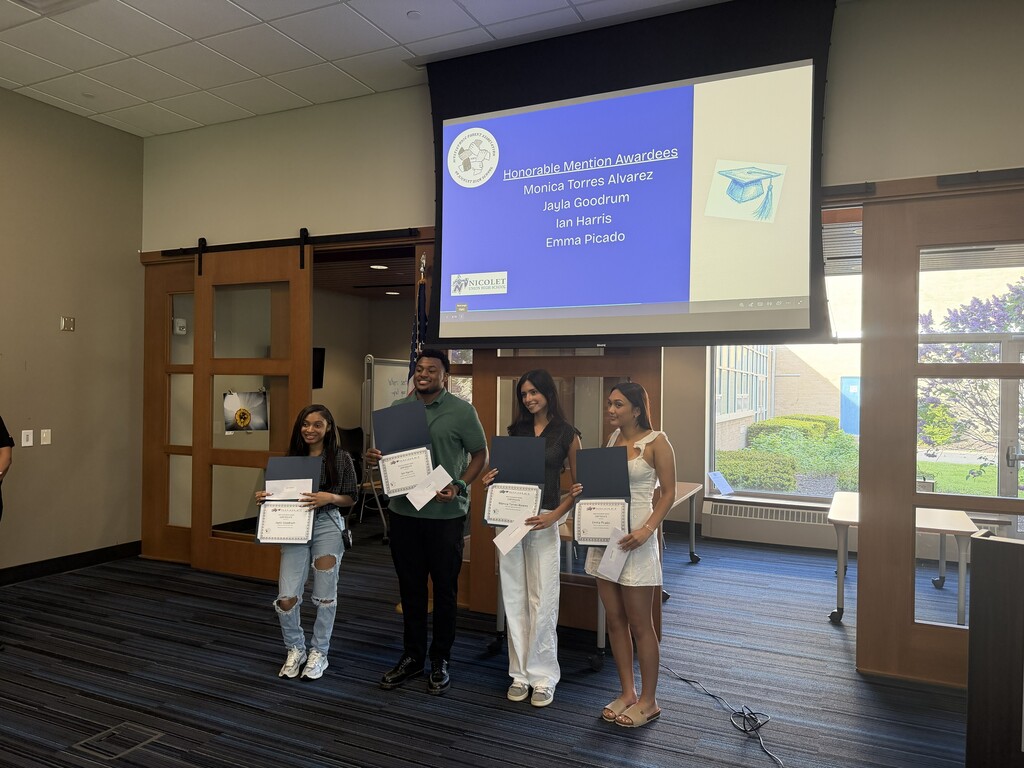 Five people stand together holding certificates, with a projection screen behind them displaying the words "Awards Ceremony".