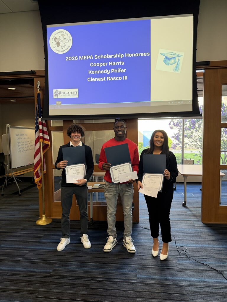 Three people stand with certificates in hand, in front of a projector screen displaying names.