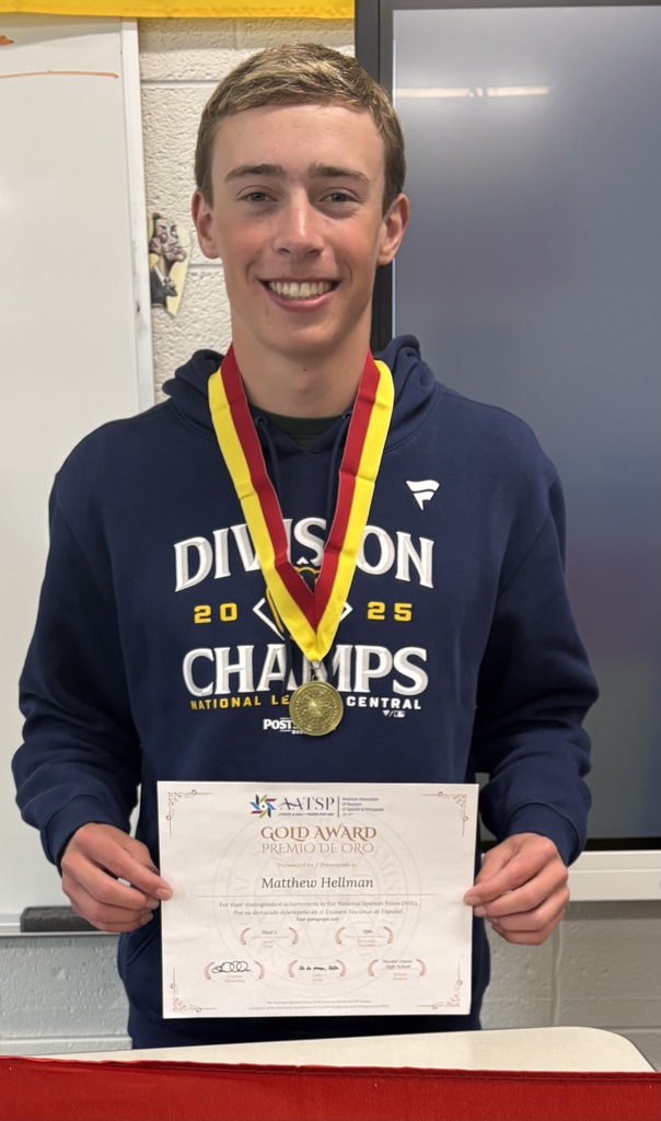 A young man wearing a blue hoodie with "Division 20 Champions" holds a gold medal and certificate.