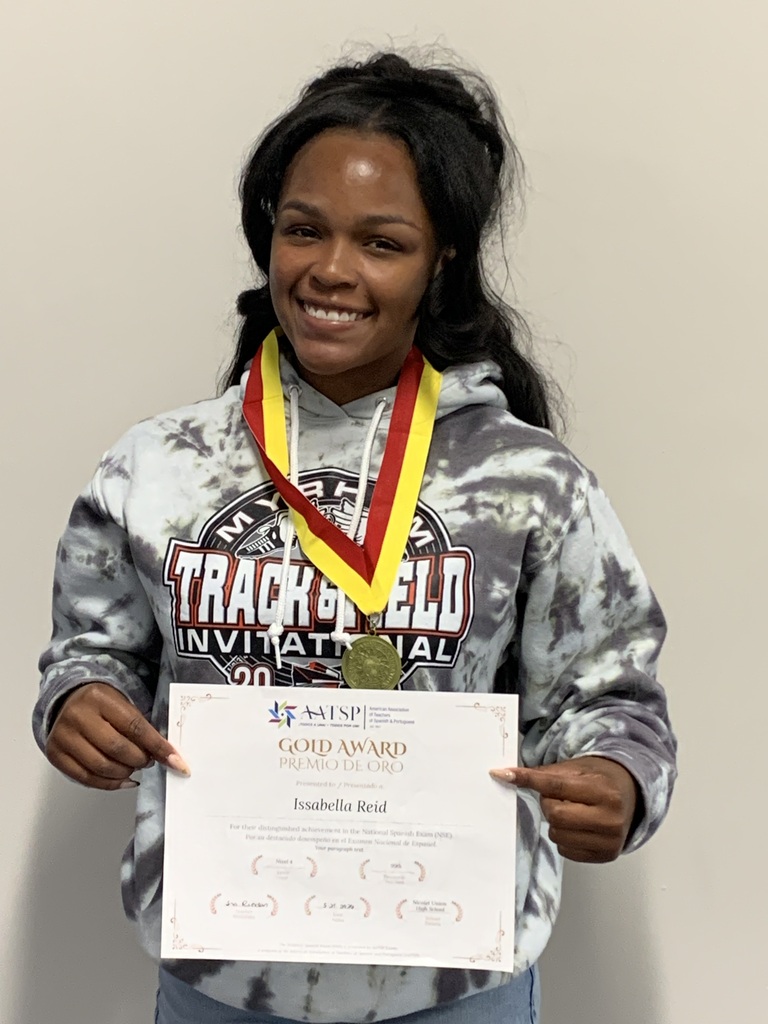 Woman in tie-dye hoodie holds certificate and gold medal. She smiles and poses for the camera.