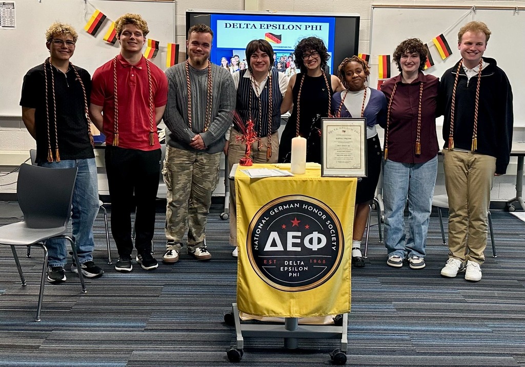 Group of people standing together, some wearing jackets, in front of a banner with the text AEP.