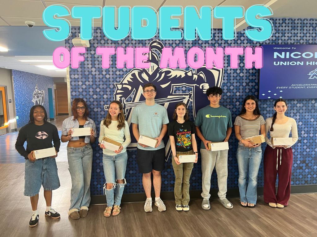 Eight students stand in front of a blue wall with text and a logo. They hold certificates.