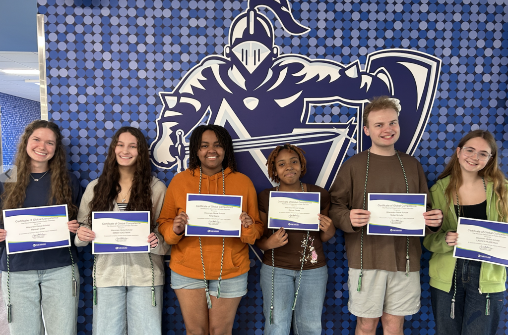 Six people pose in front of a wall, each holding a certificate. They stand in two rows.