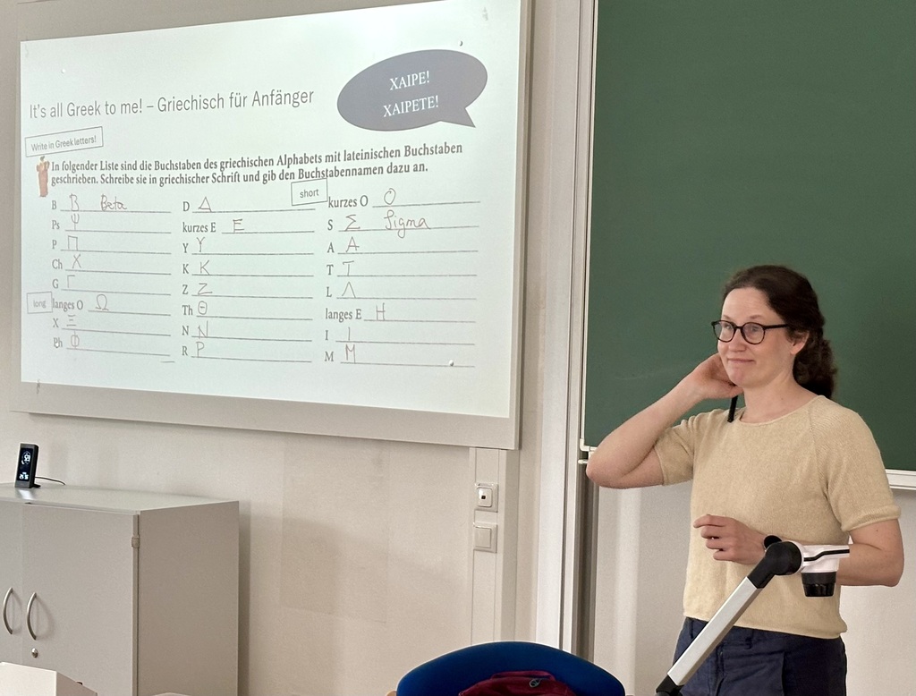 Woman in front of a classroom whiteboard with a large white sheet of paper and a speech bubble.